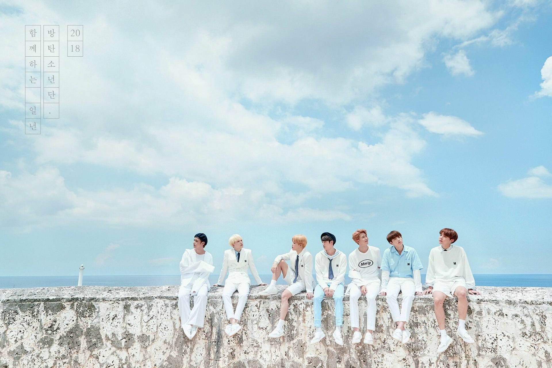 Bts Sitting On Stone Border Under Sky Background