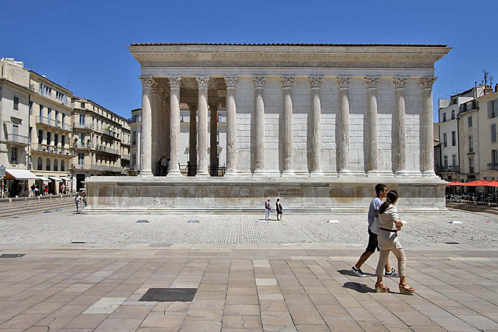 Bustling Day At The Historic Maison Carrée Background
