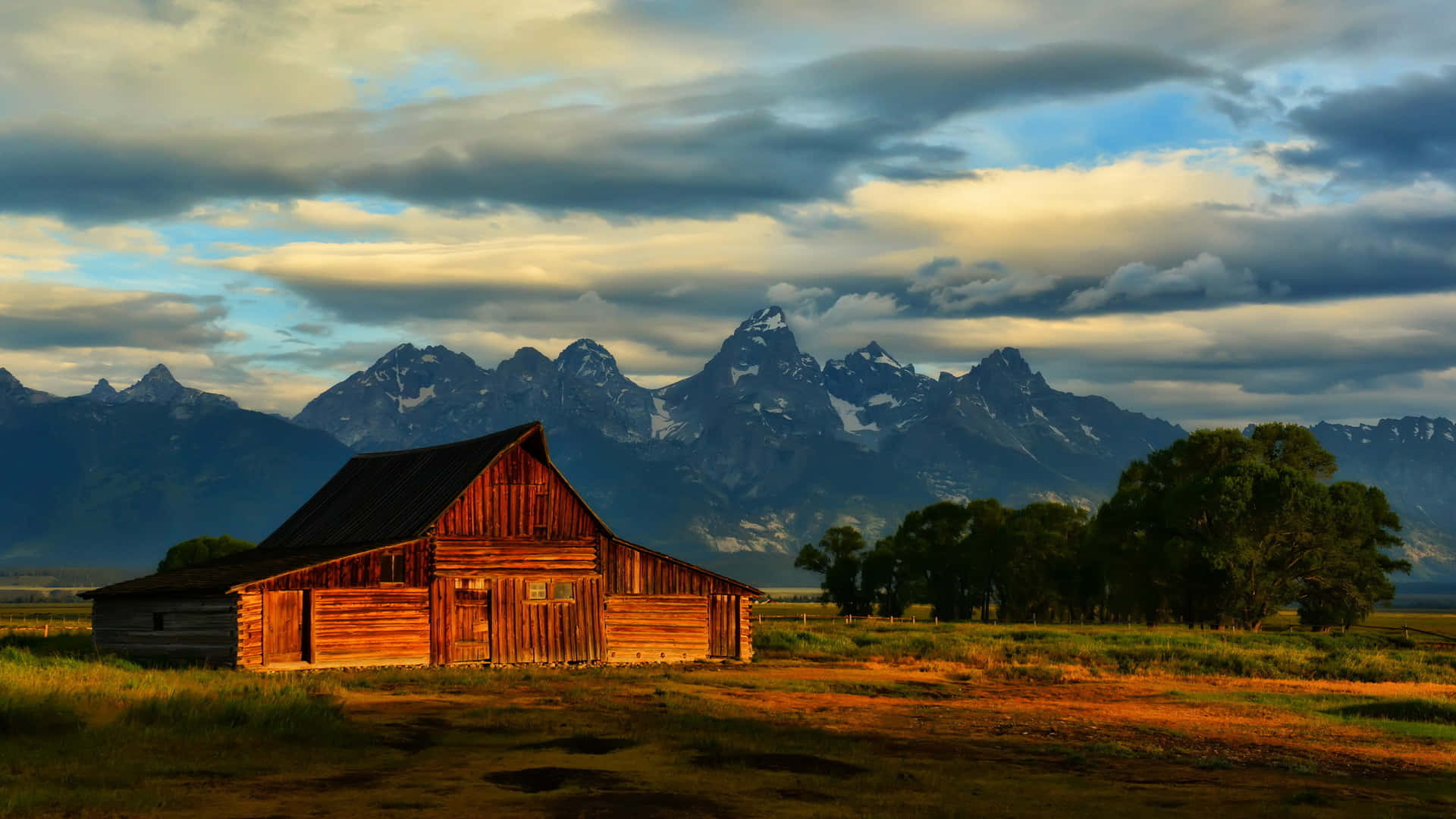Cabin In The Field Overlooking Mountains Background