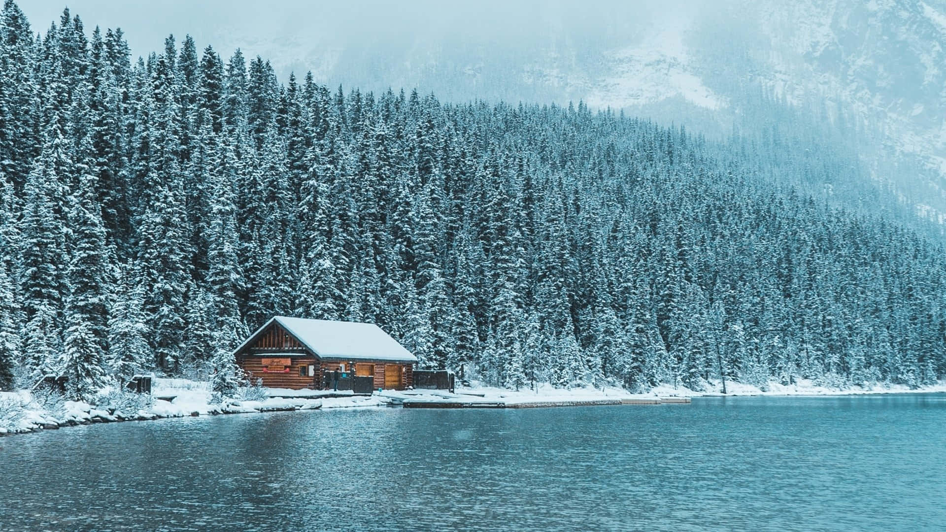 Cabin Snow Covered By The Lake Background