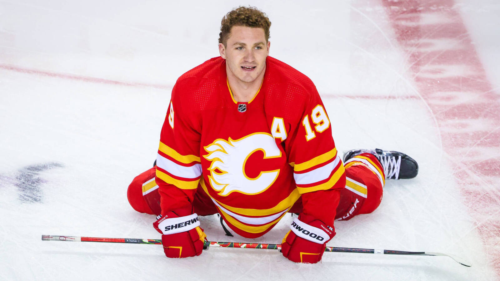 Calgary Flames Matthew Tkachuk Sitting On Rink Background