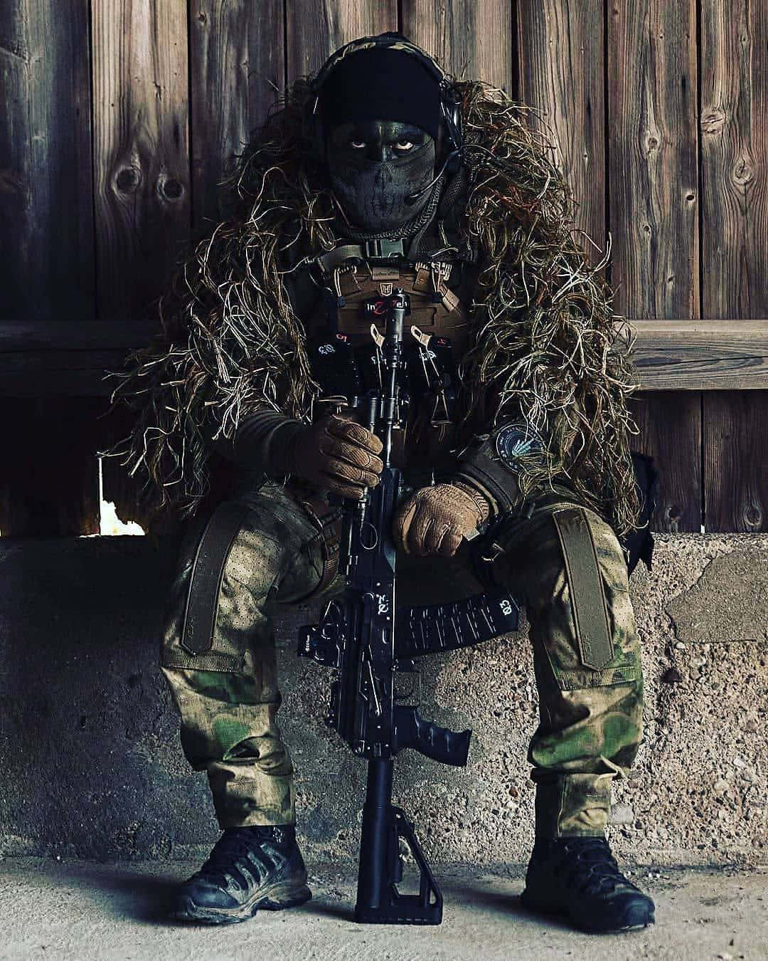 Camouflaged Sniper Sitting With Rifle