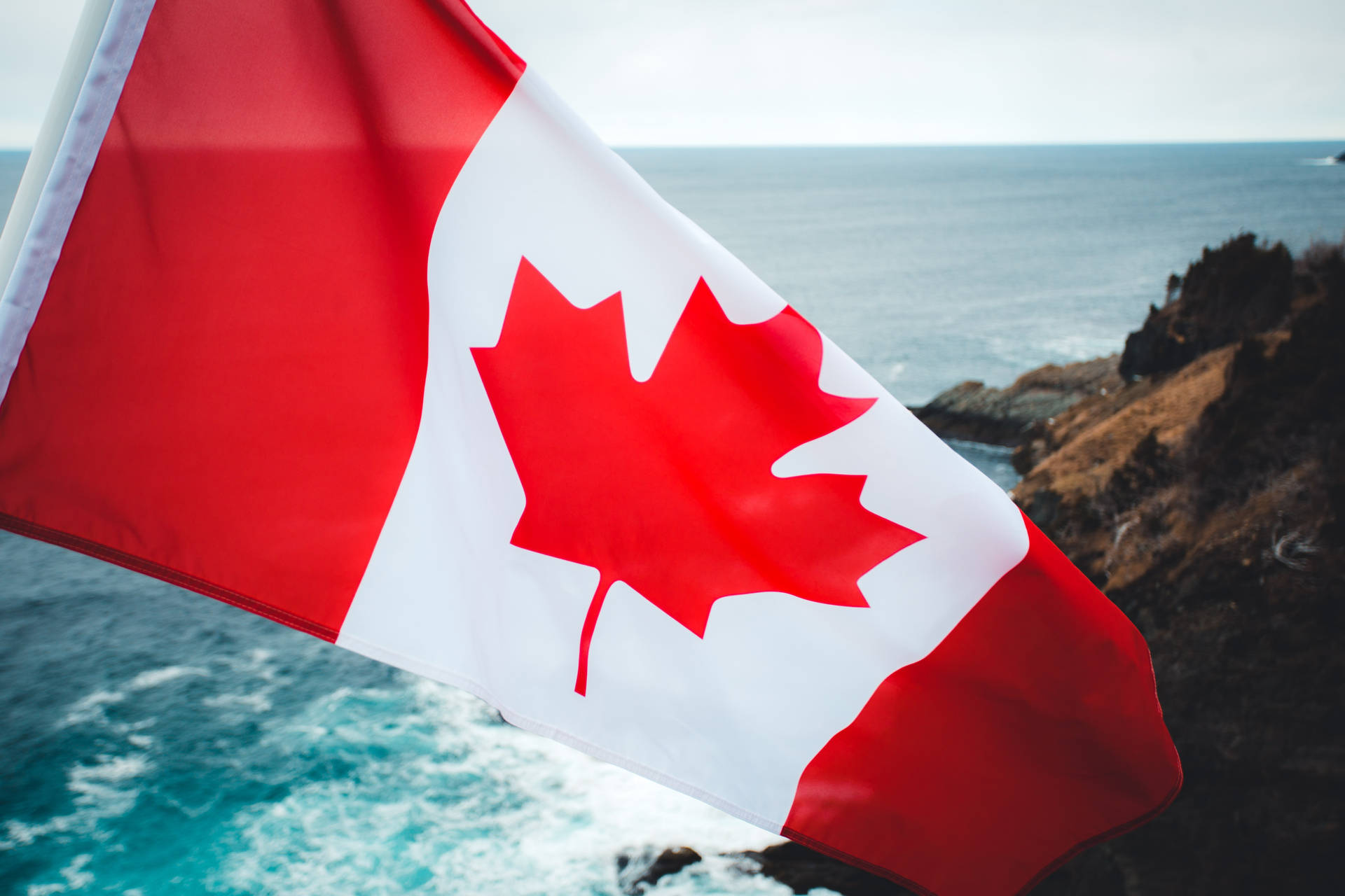 Canadian Flag Rocky Cliff Sea Background