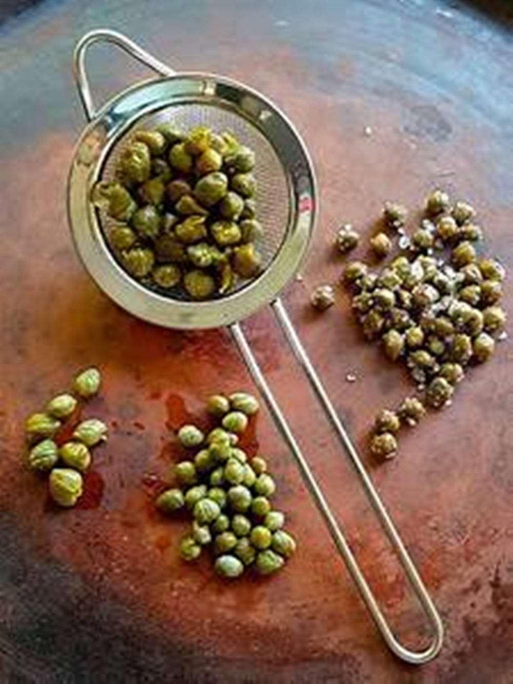 Capers In Mini Strainer On Wood Board