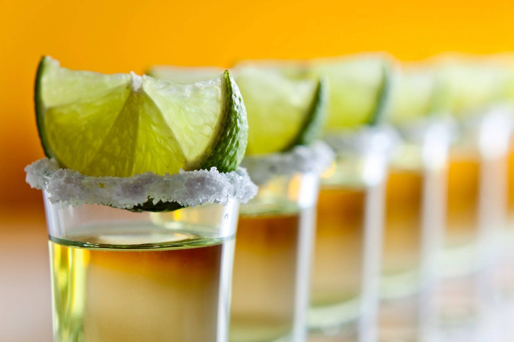 Caption: A Vibrant Showcase Of Tequila Shots With Lime Garnish Background