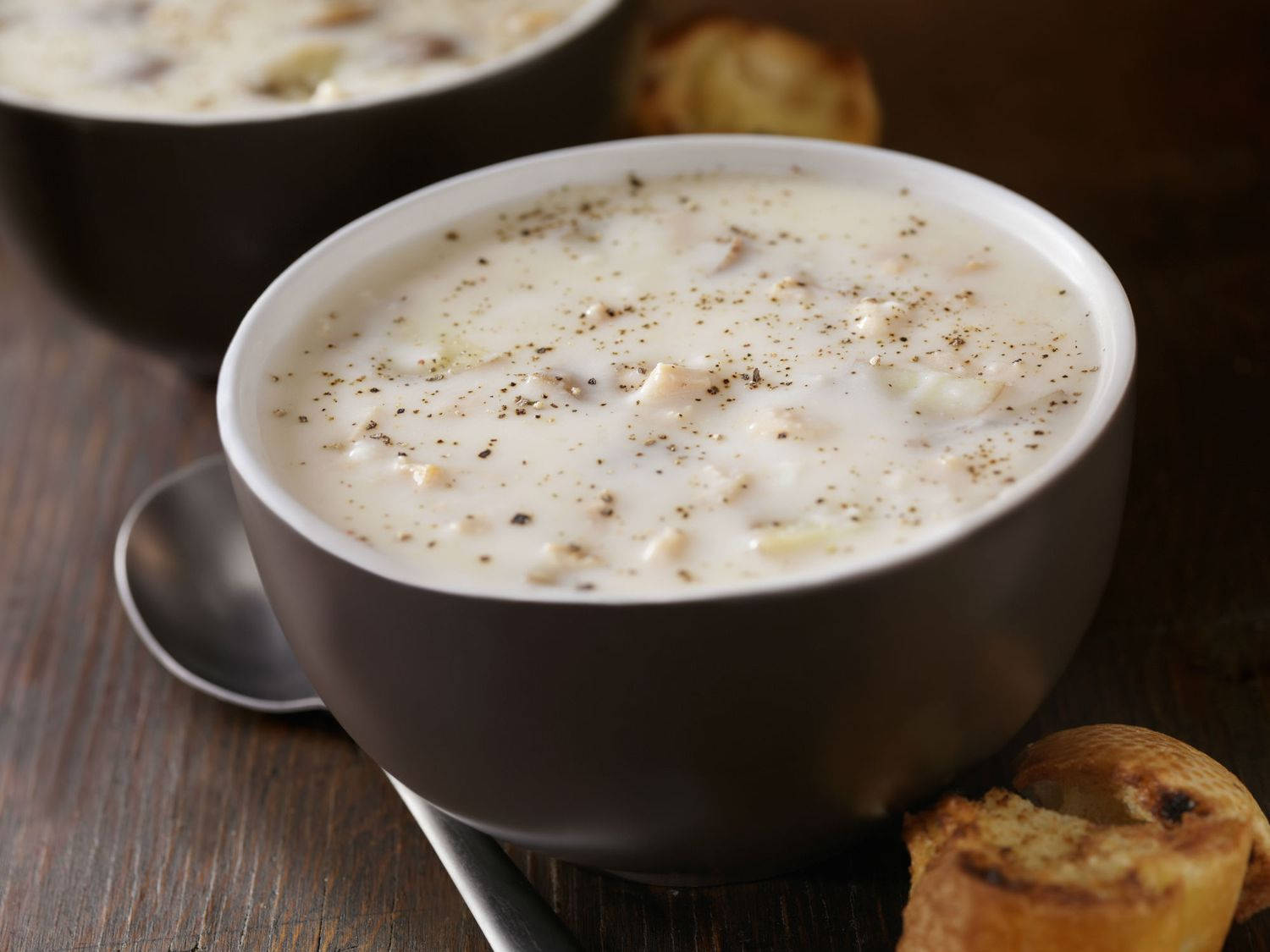 Caption: A Warm Bowl Of New England Clam Chowder With Toasted Bread Background