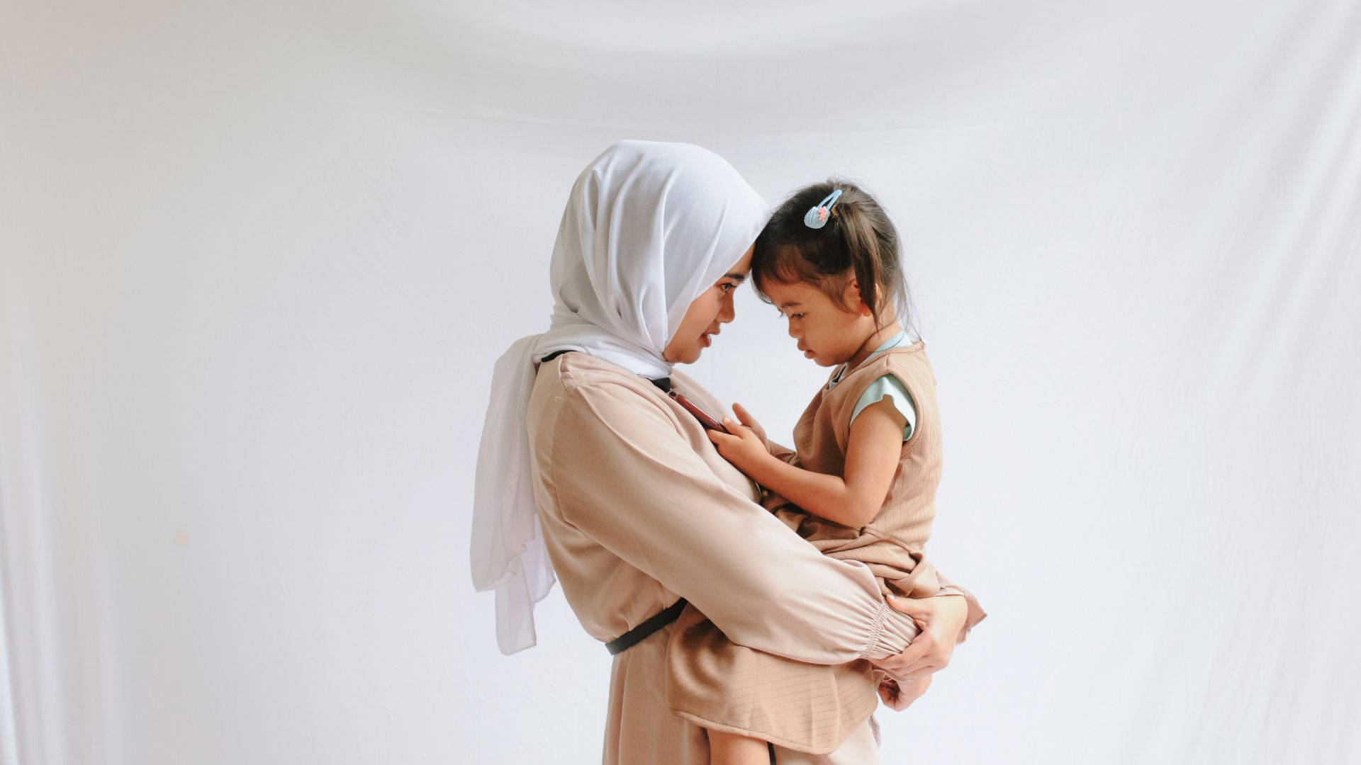 Caption: A Warm Embrace - Loving Muslim Mother Carrying Her Child Background
