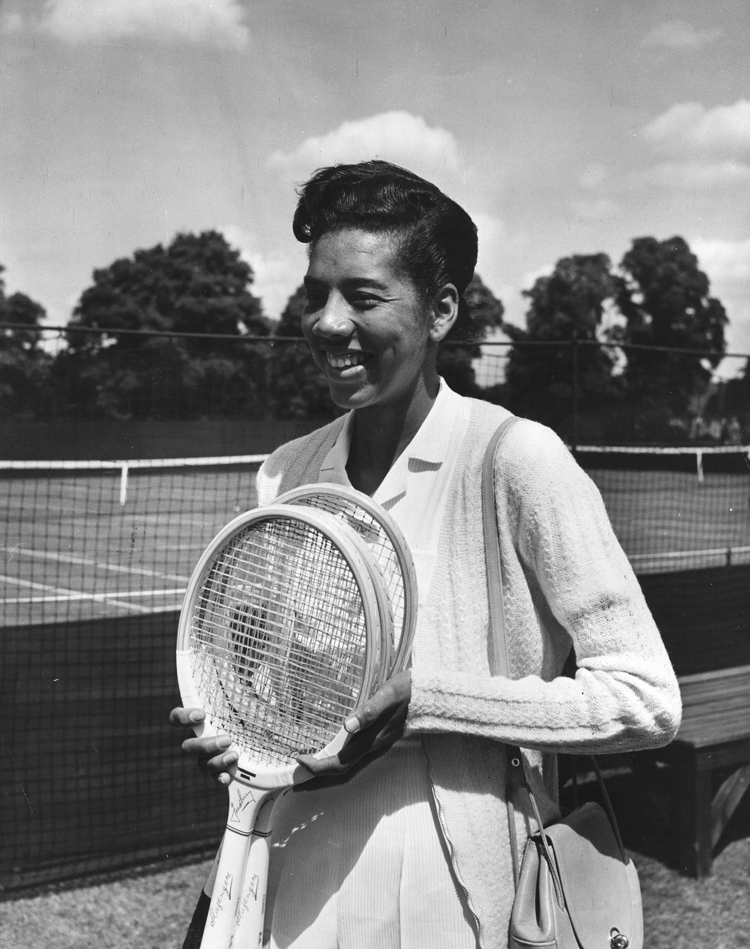 Caption: Althea Gibson Triumphantly Holding A Tennis Racket Background