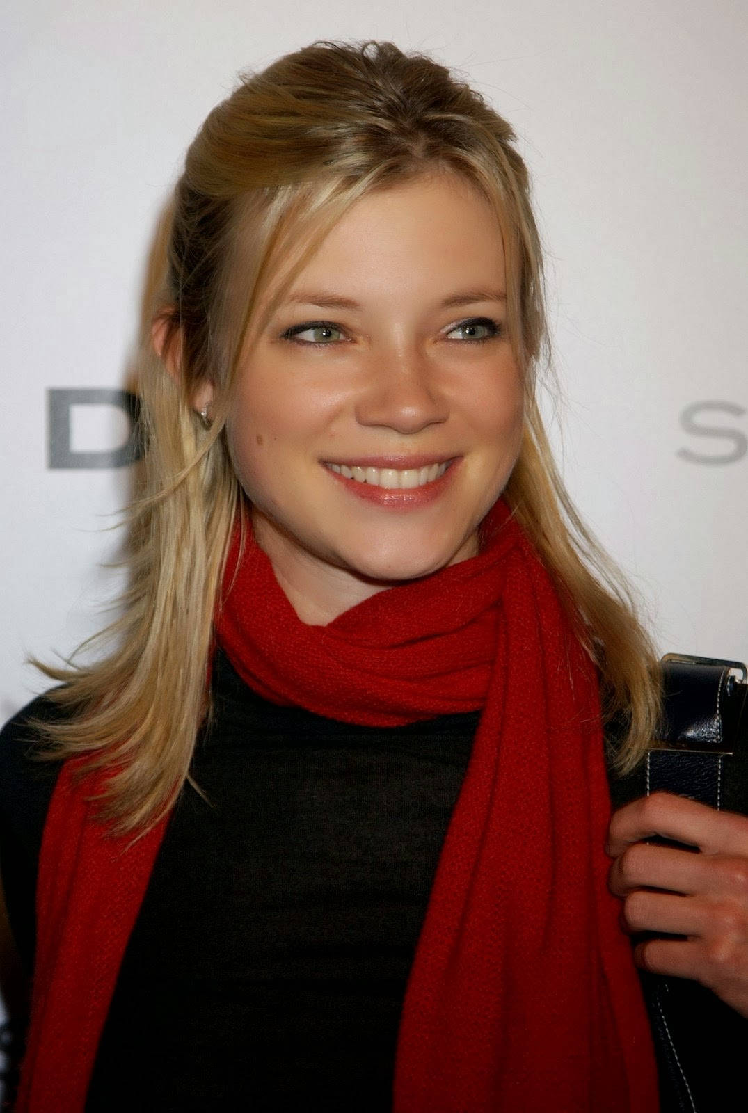 Caption: Amy Smart Radiating Elegance In A Black Dress And Red Scarf Background