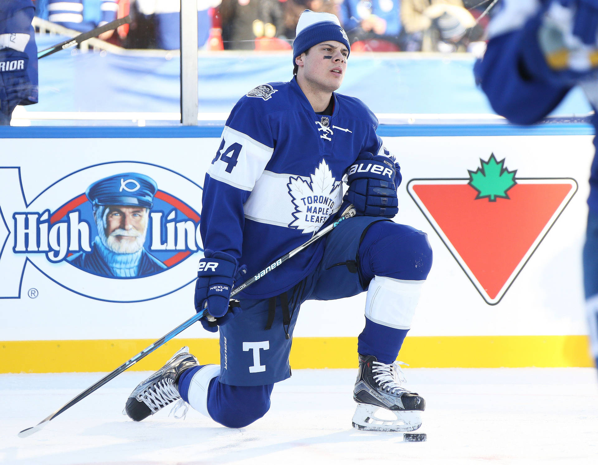 Caption: Auston Matthews Kneeling On Ice Background