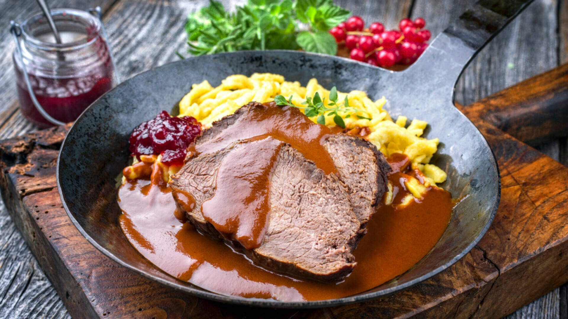 Caption: Authentic German Sauerbraten Dish With Redcurrant Jam And Basil Background