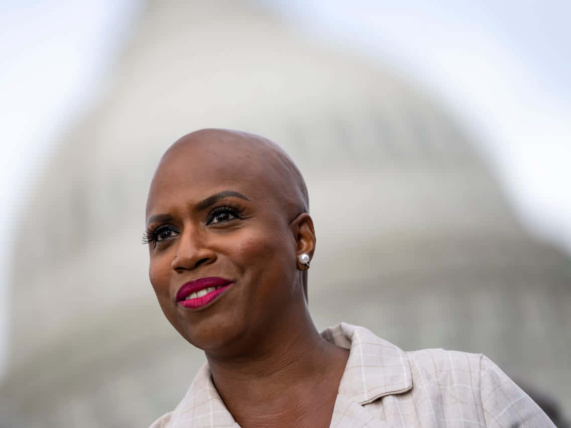Caption: Ayanna Pressley Standing Strong Against Blurred Backdrop Of The Capitol