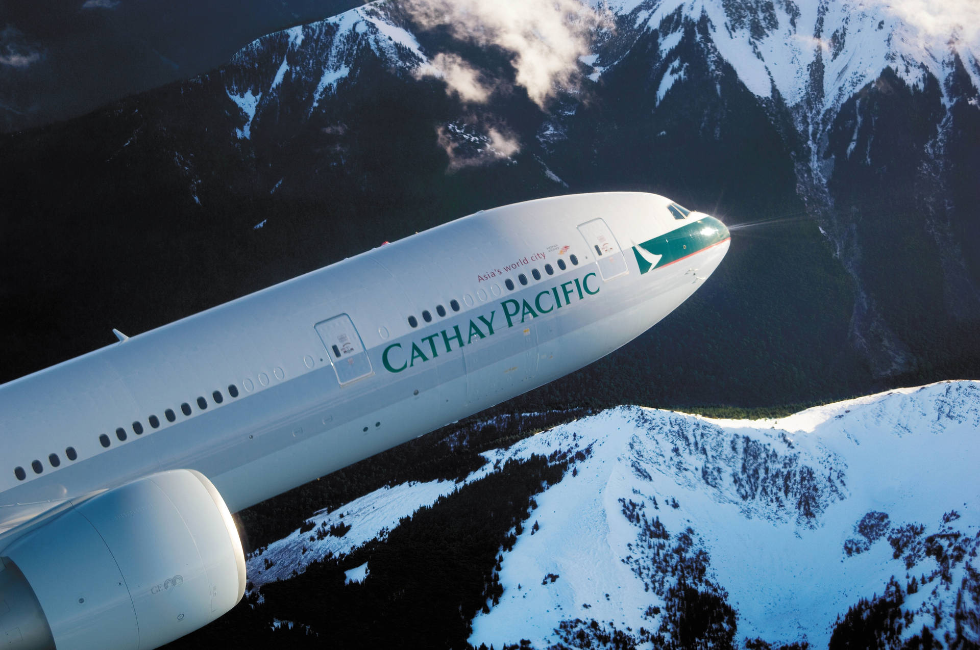 Caption: Cathay Pacific Jet Over Snow-capped Mountains Background