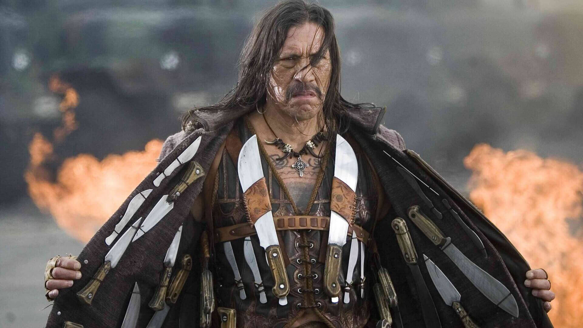 Caption: Danny Trejo Posing With Weapons As Machete Background