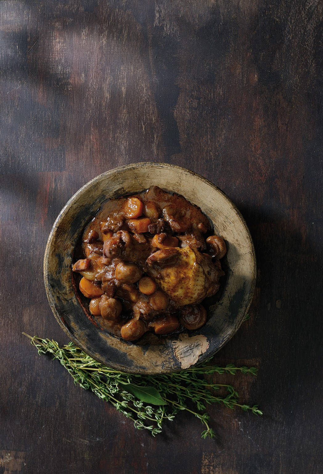 Caption: Decadent Coq Au Vin Dish Served Beside Aromatic Rosemary Leaves