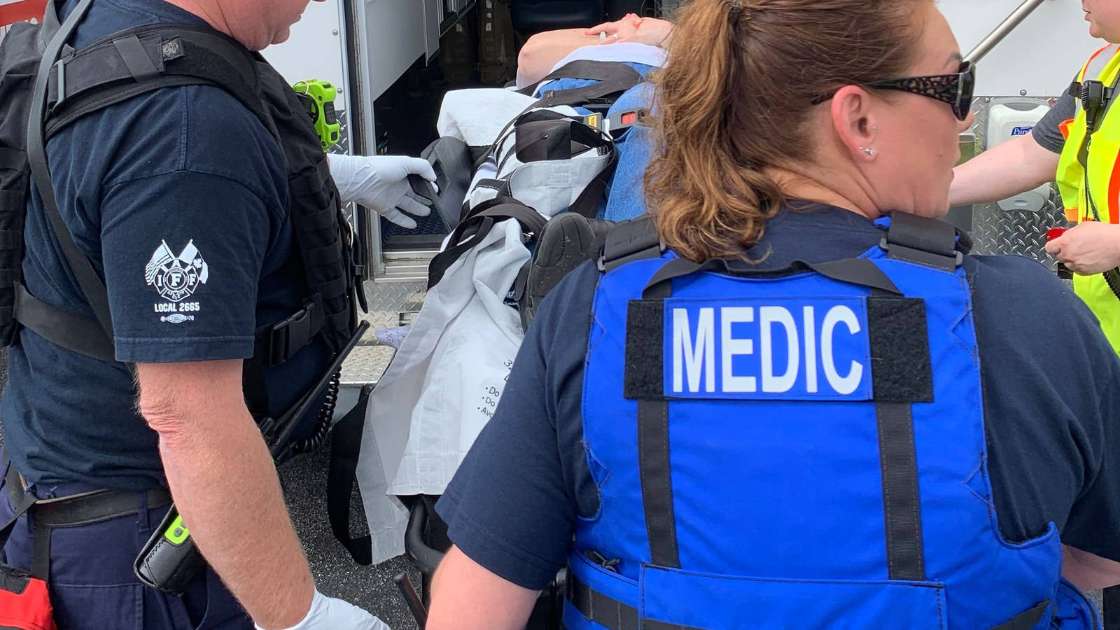 Caption: Dedicated Female Paramedic Assisting At The Scene Background