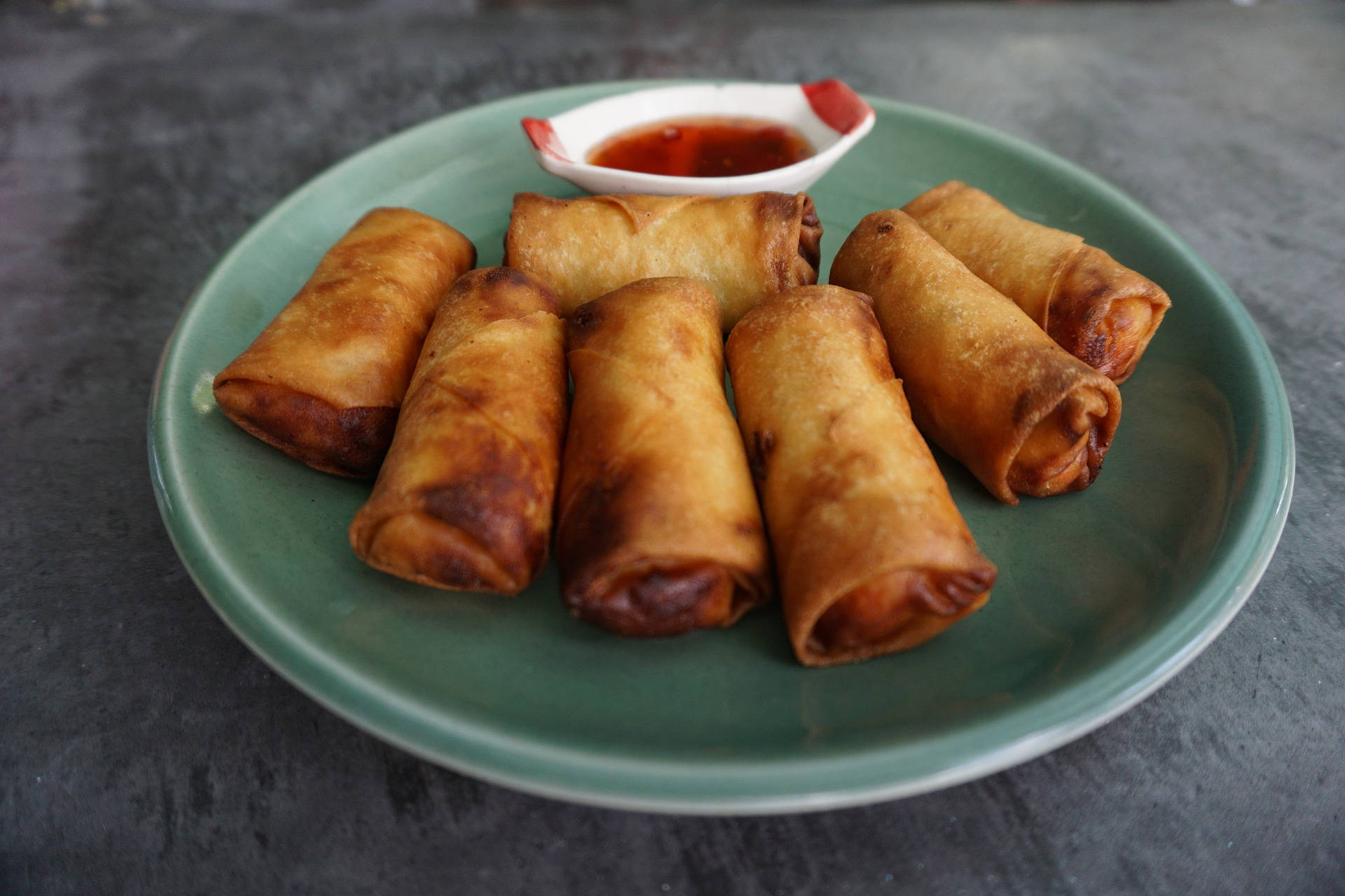 Caption: Deliciously Crisp Egg Rolls On A Simple Plate Background