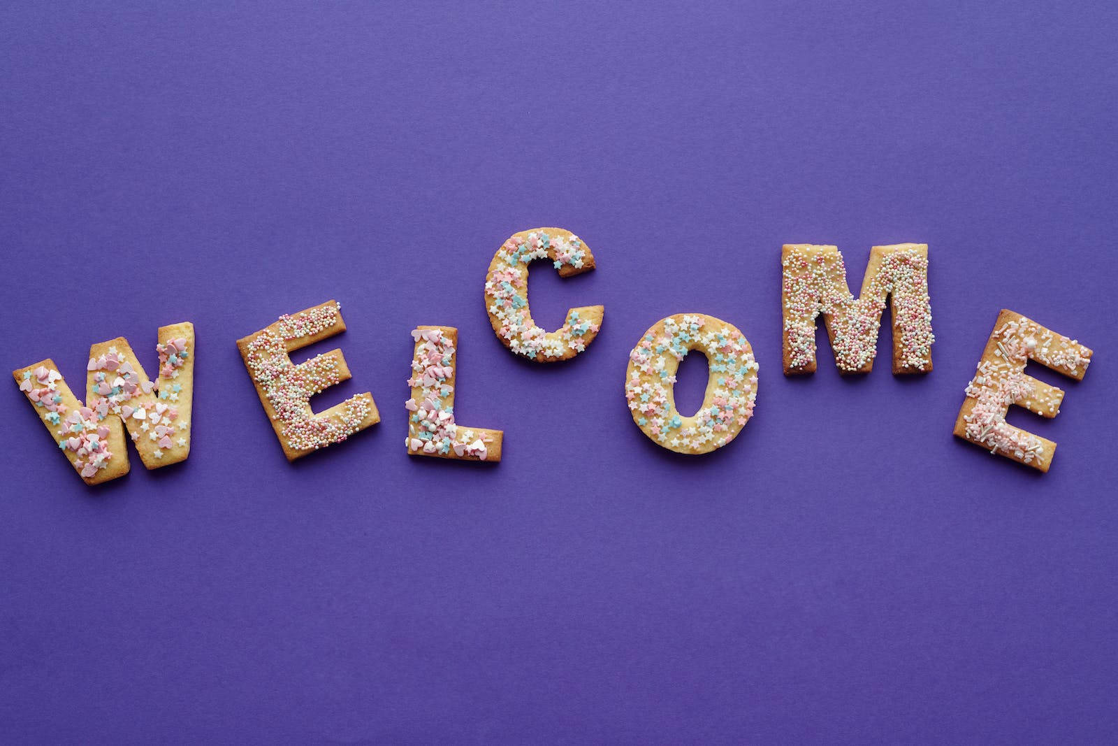 Caption: Delightful Welcome Cookies In Letter Shapes Background