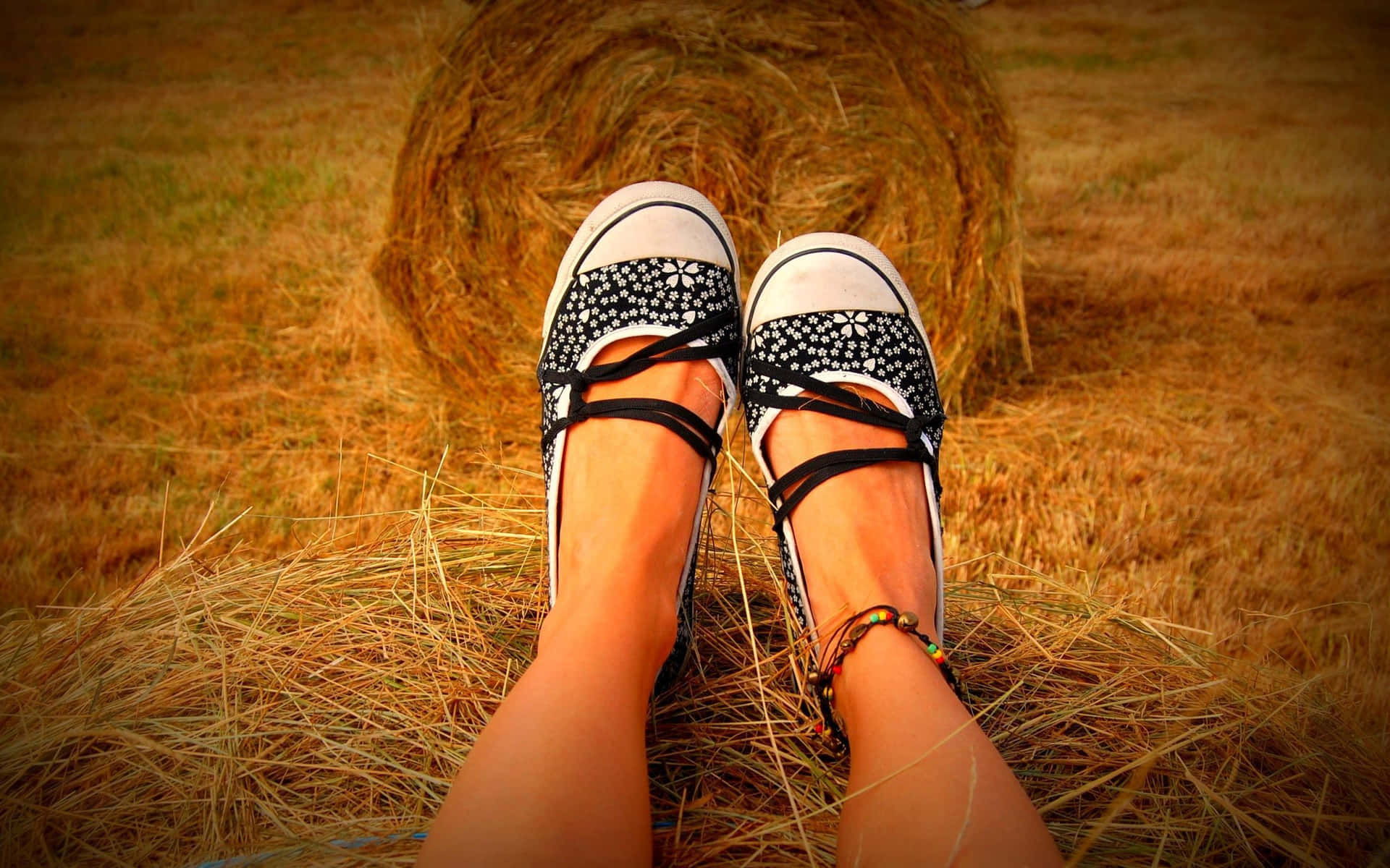 Caption: Elegant Girl Feet Sporting Black And White Shoes On Hay Bale Background