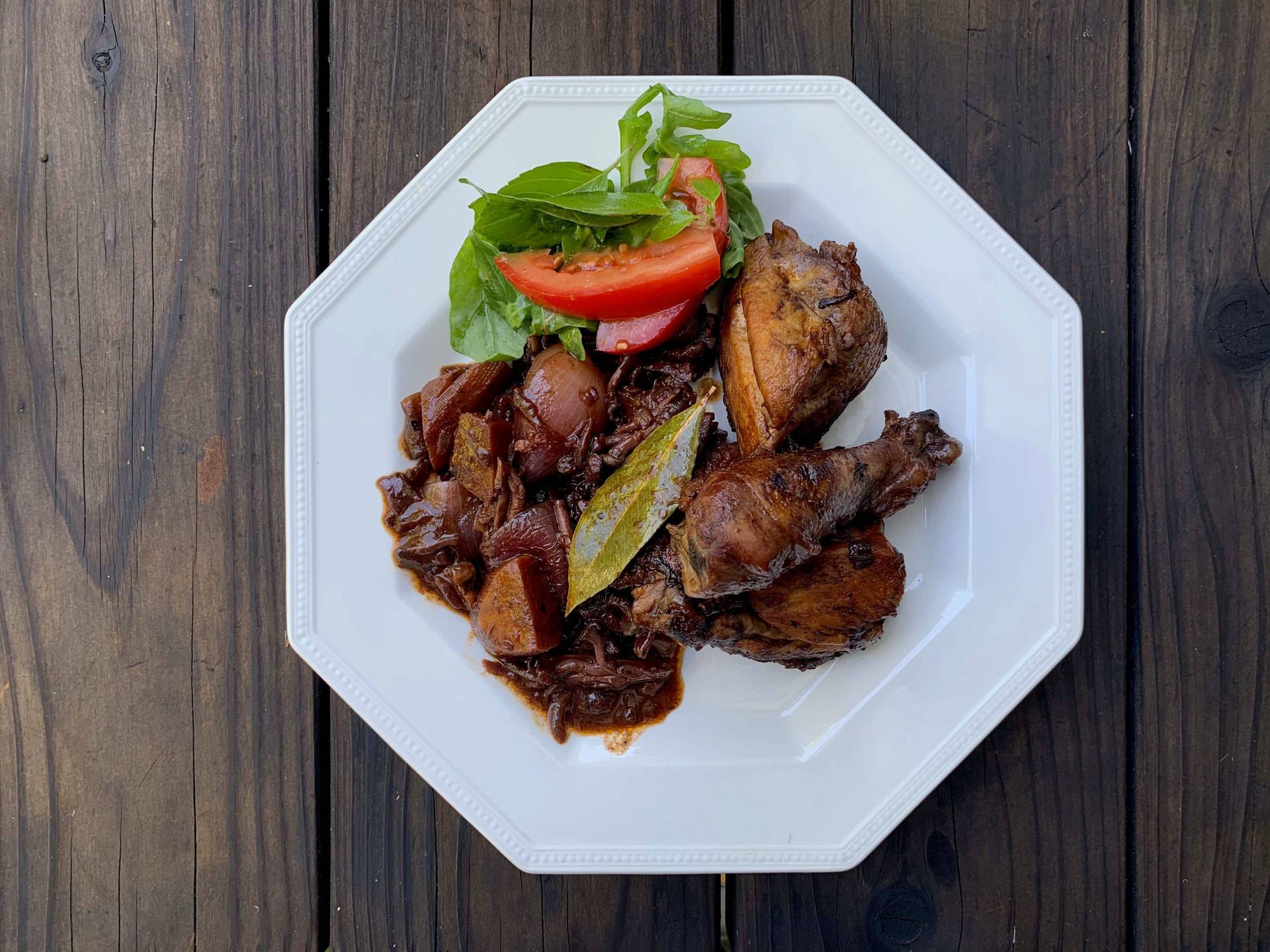 Caption: Exquisite Coq Au Vin Served On Sleek White Hexagonal Plate Background