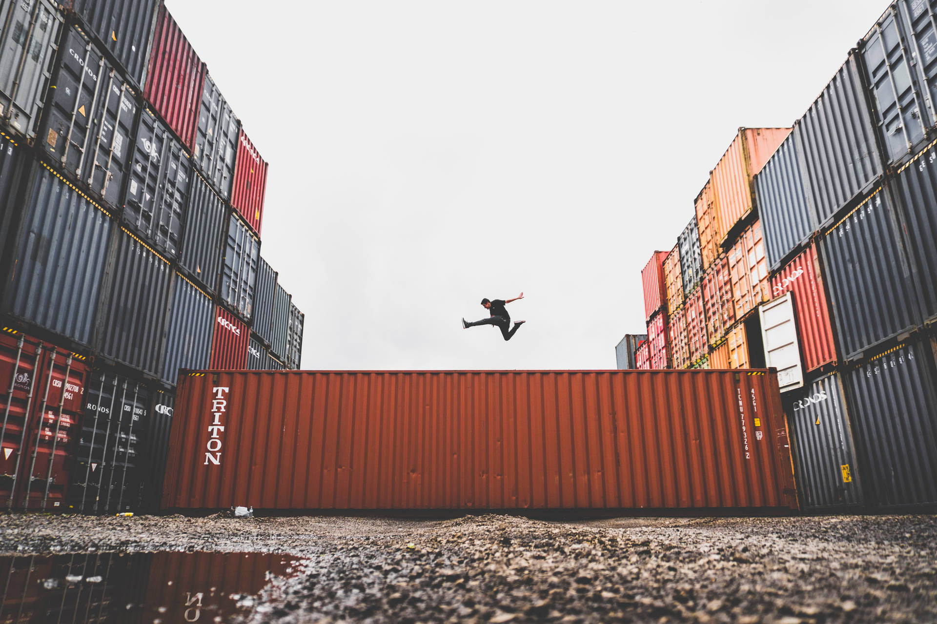 Caption: Fearless Leap Amidst Shipping Containers