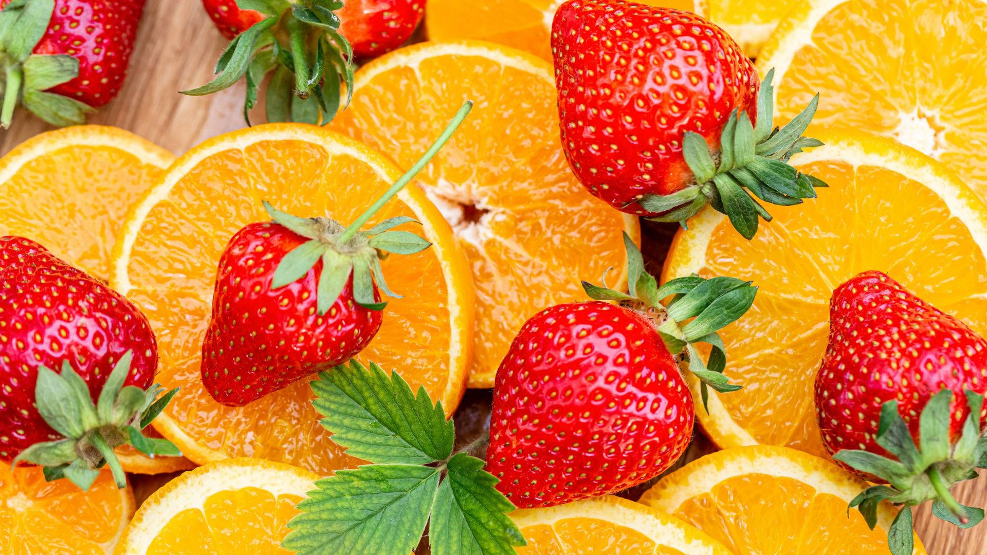 Caption: Fresh Orange Fruits With Ripe Red Strawberries Background