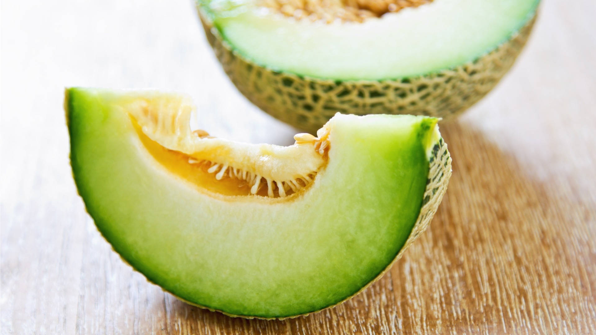 Caption: Freshly Sliced Honeydew Melon On A Rustic Wooden Table Background