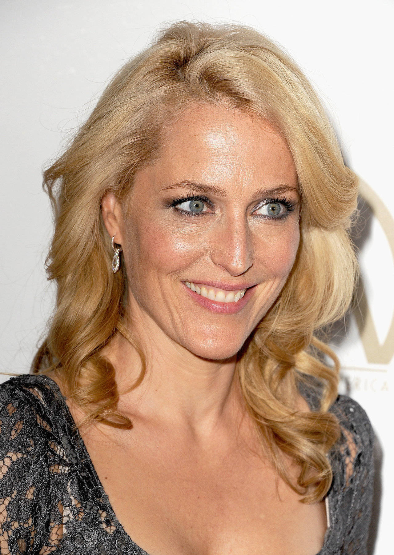Caption: Gillian Anderson Showcasing A Curly Blonde Hairstyle. Background