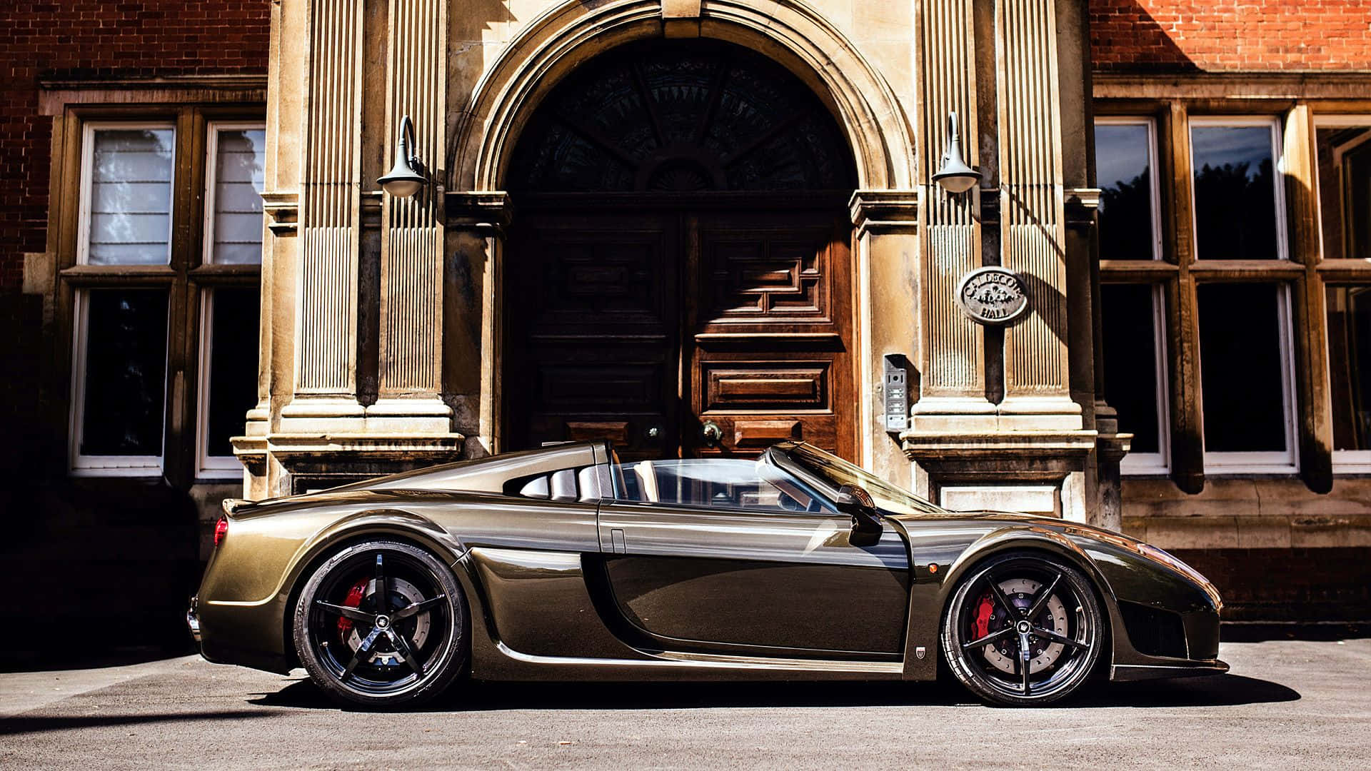 Caption: Gleaming Golden Black Noble M600 Super Car Background