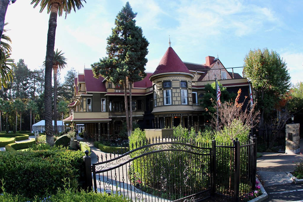 Caption: Historic Winchester Mystery House Surrounded By Greenery Background