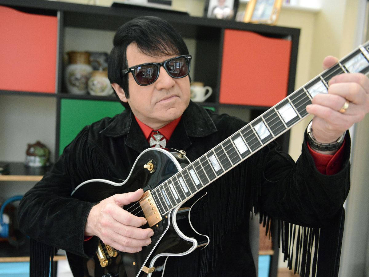 Caption: Iconic Musician Roy Orbison Masterfully Playing His Guitar