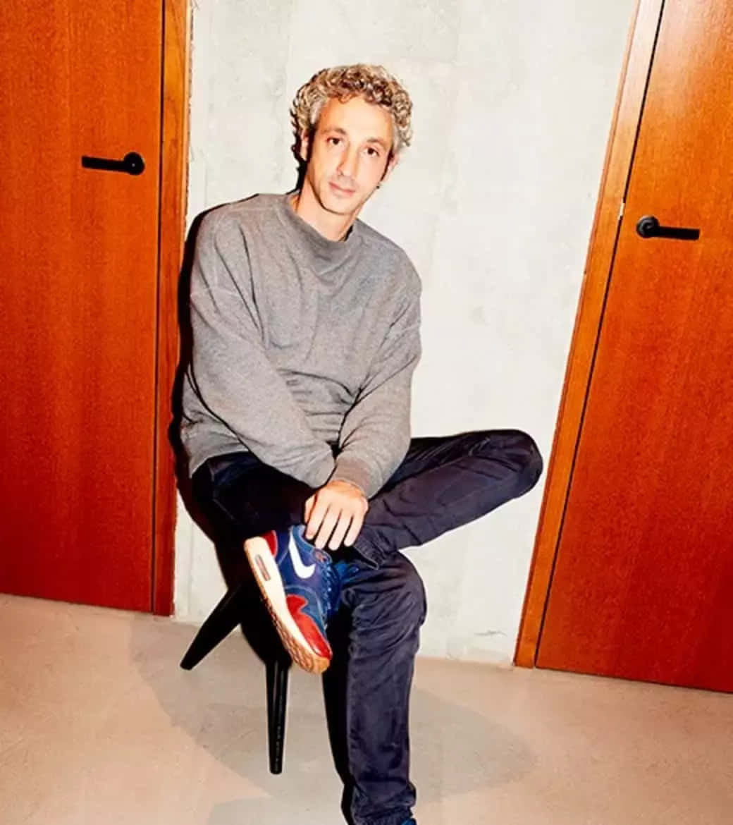 Caption: Jérôme Dreyfuss Posing Thoughtfully On A Chair Background