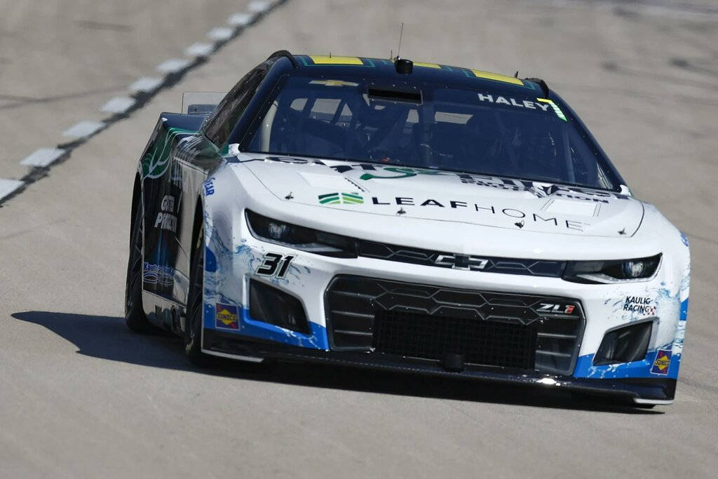 Caption: Justin Haley Triumphantly Drives His Number 16 White Racing Car. Background