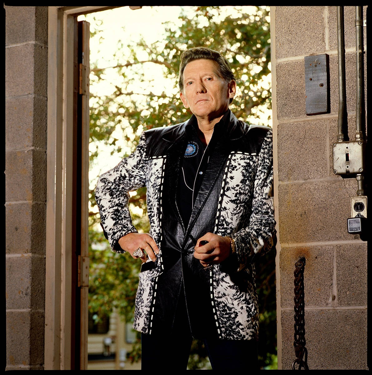 Caption: Legendary Rock 'n' Roll Pioneer, Jerry Lee Lewis Leaning On A Doorway Background