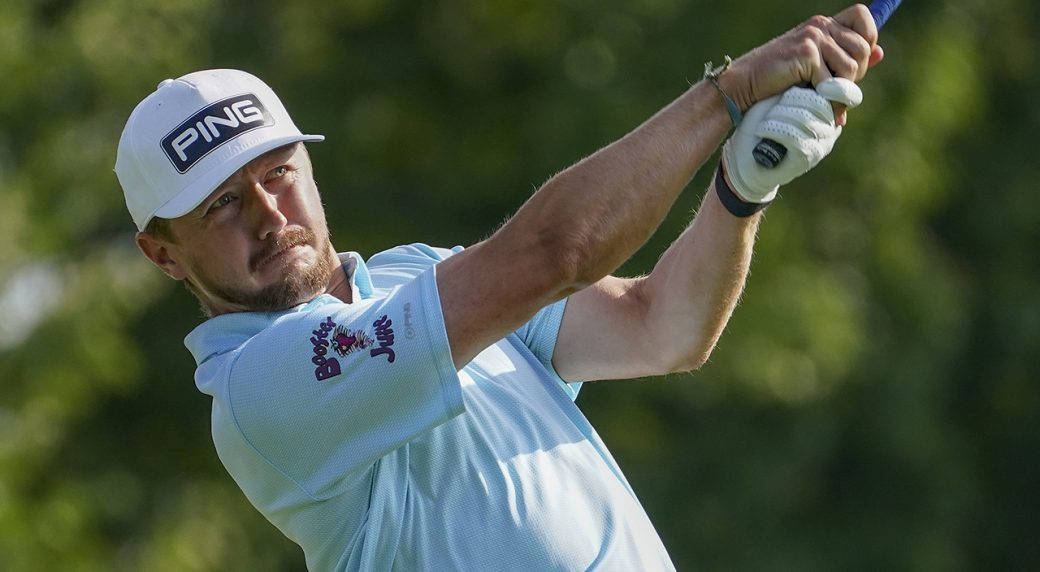 Caption: Mackenzie Hughes Focusing On His Swing On The Golf Course Background