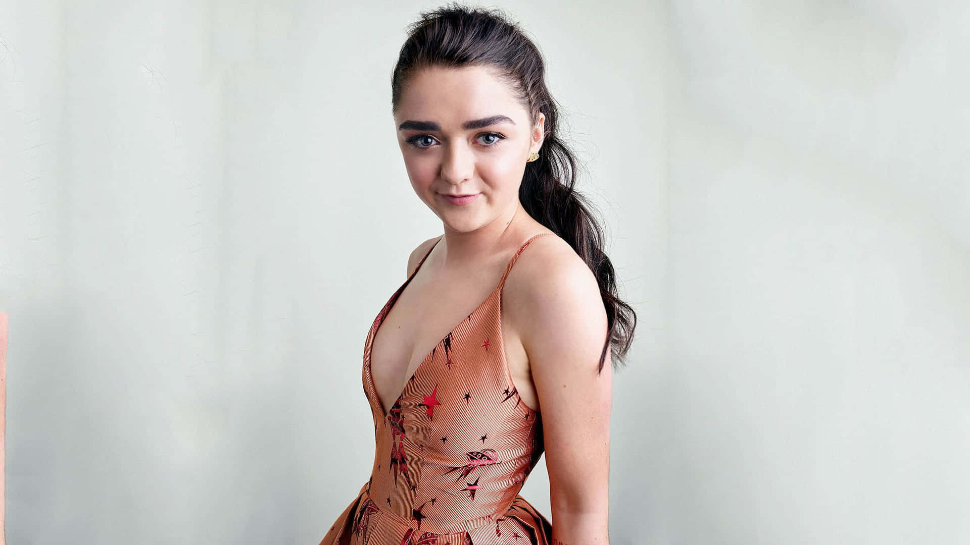 Caption: Maisie Williams Wearing A Formal Dress And Smiling At The Camera During An Event Background