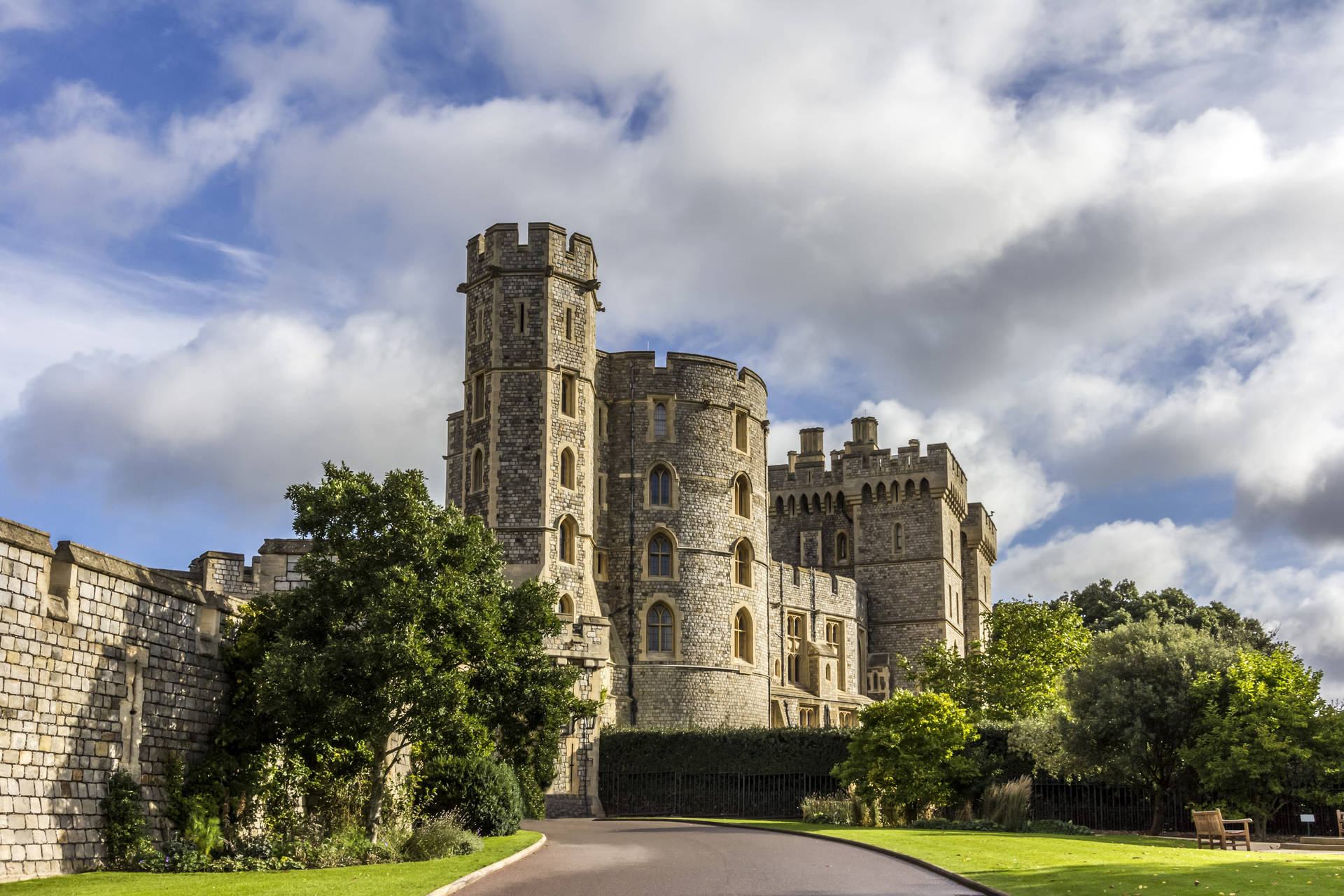 Caption: Majestic Windsor Castle Nestled Among Lush Greenery Against A Dramatic Cloudy Sky Background