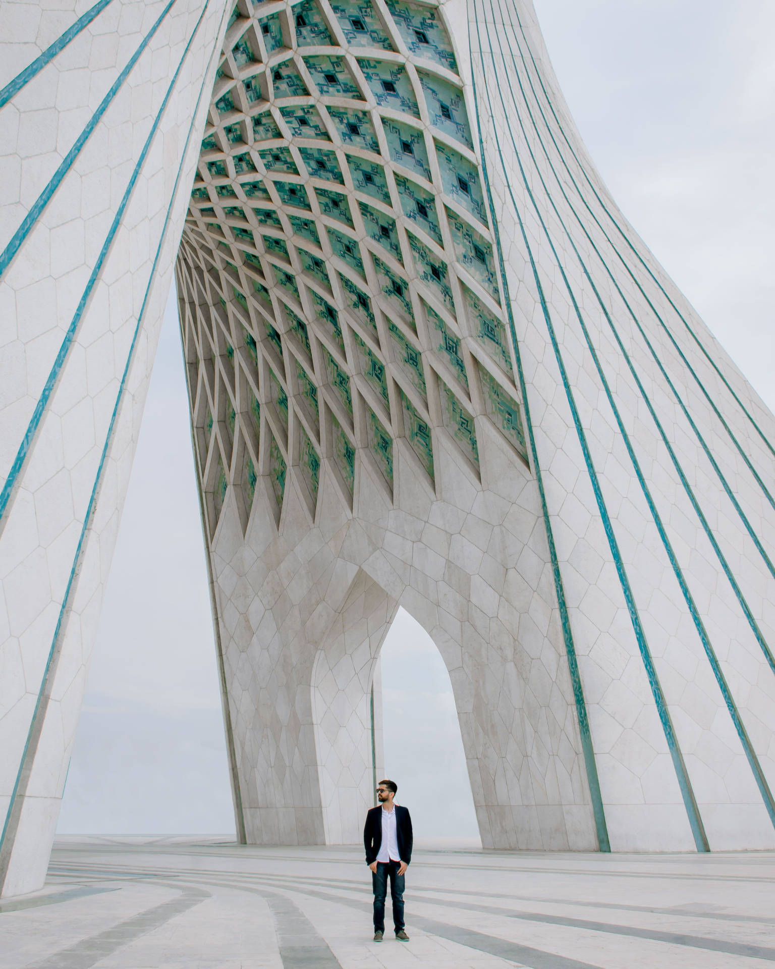 Caption: Man Standing In Front Of The Azadi Tower In Tehran, Iran Background
