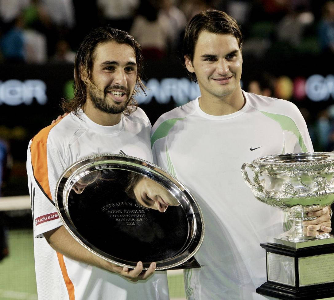 Caption: Marcos Baghdatis Engrossed In A Gripping Match With Roger Federer Background