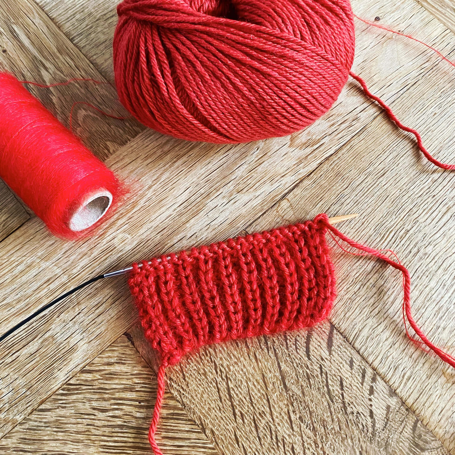 Caption: Passionate Hands Knitting A Red Cotton Yarn Background