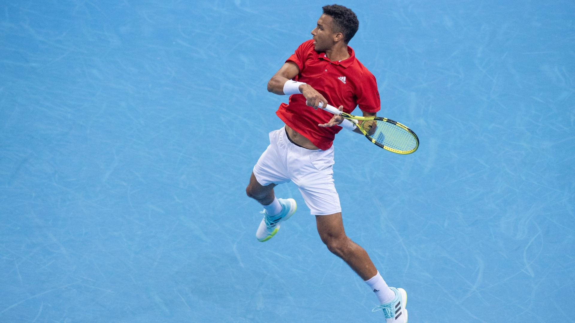 Caption: Professional Tennis Player Felix Auger Aliassime Showcasing His Footwork Skills Off The Court Background