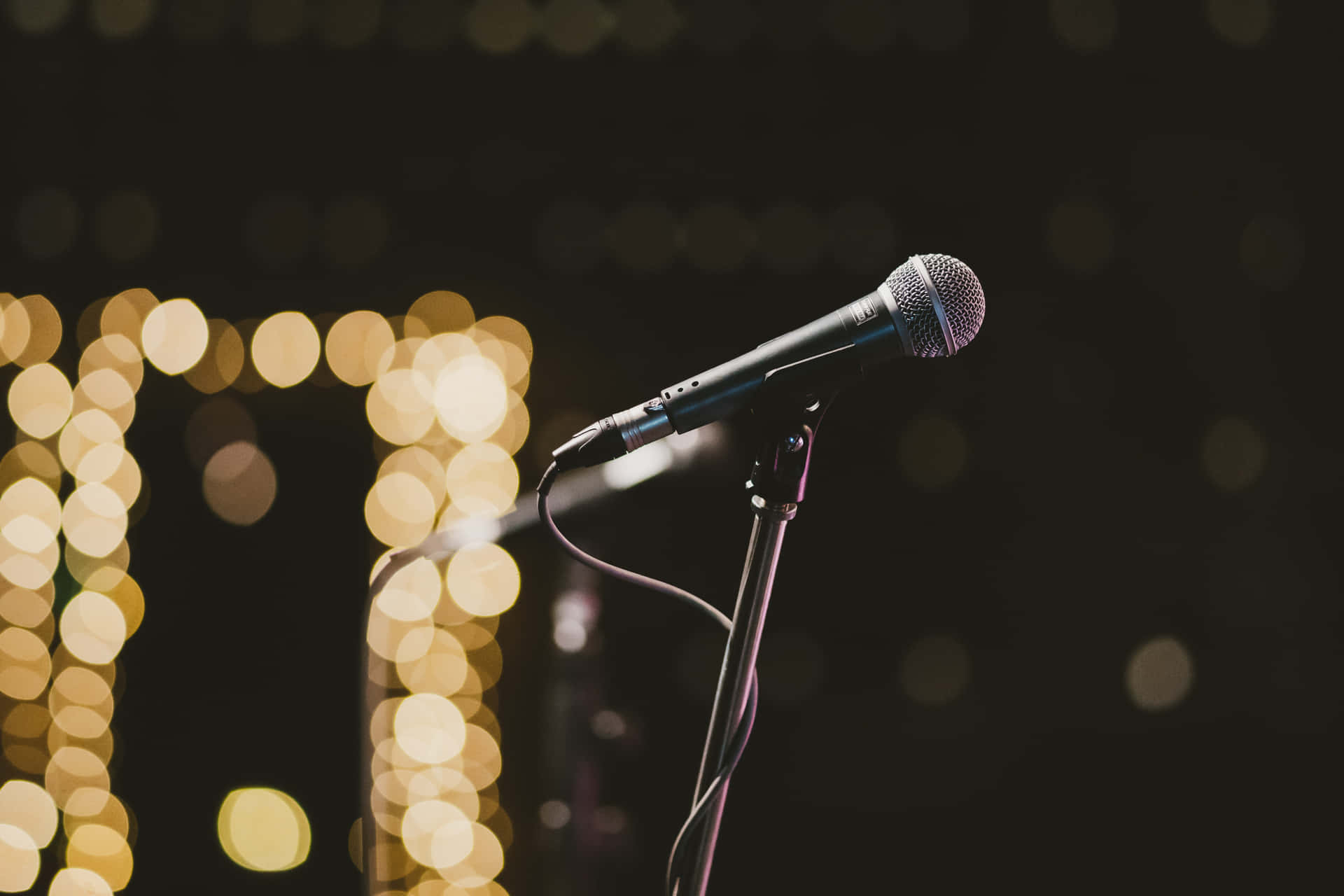 Caption: Retro Microphone Bathed In Warm Stage Lights Background