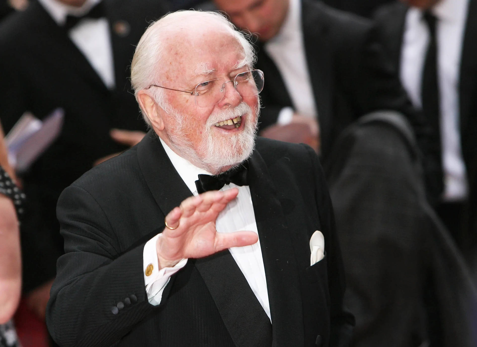 Caption: Richard Attenborough Enthusiastically Waving On The Red Carpet