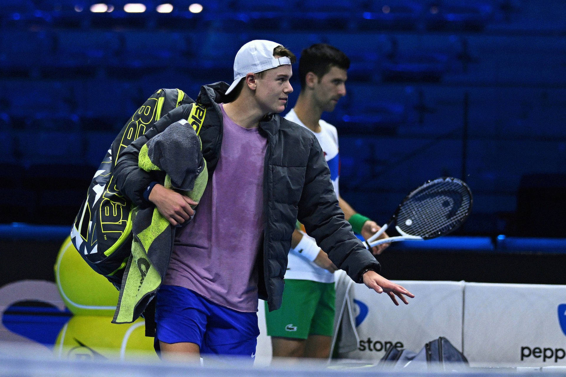 Caption: Rising Star Holger Rune In Mid-action On The Tennis Court Background