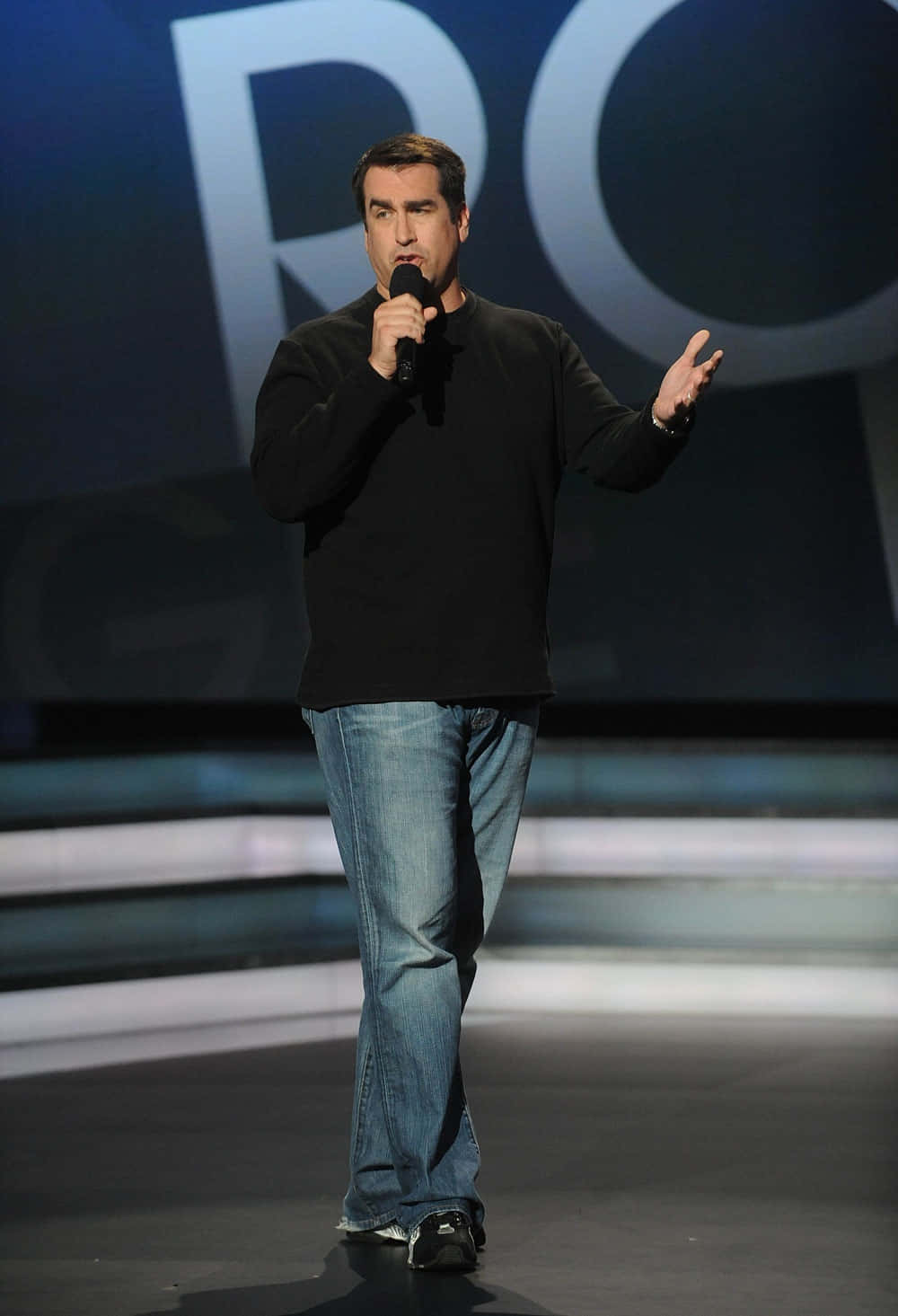 Caption: Rob Riggle Showcasing His Jovial Personality In A Professional Photoshoot. Background