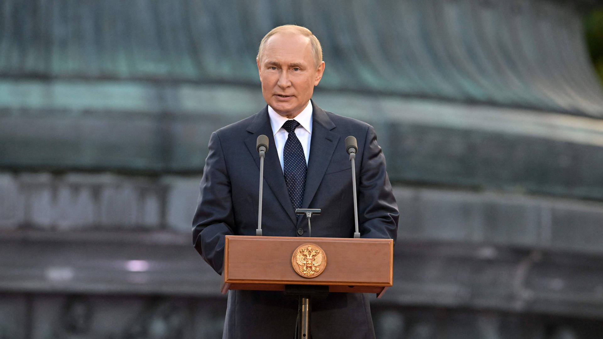 Caption: Russian President Vladimir Putin Delivering A Speech At A Ceremonial Event. Background