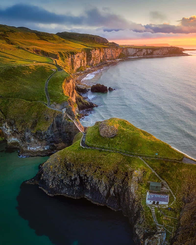 Caption: Scenic View Of Carrick-a-rede Rope Bridge In Northern Ireland Background