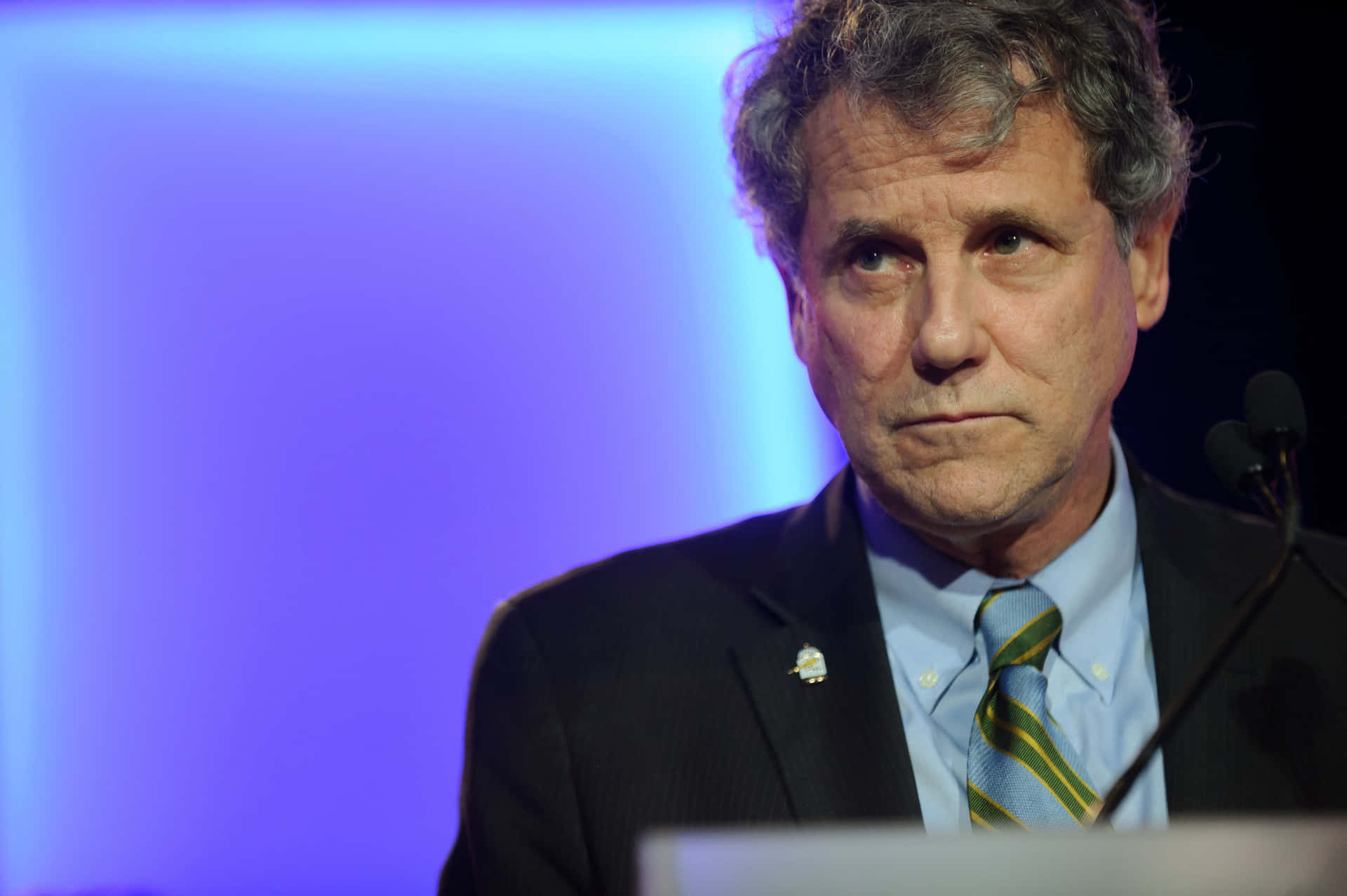 Caption: Sherrod Brown With A Frowning Facial Expression Background