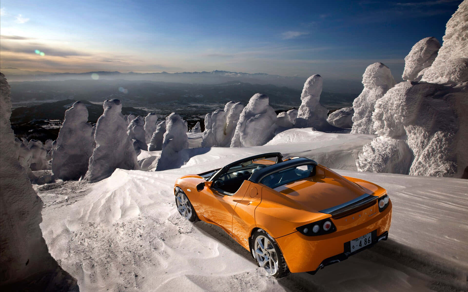 Caption: Sleek And Sophisticated Tesla Roadster Parked In A Glowing Spotlight Background
