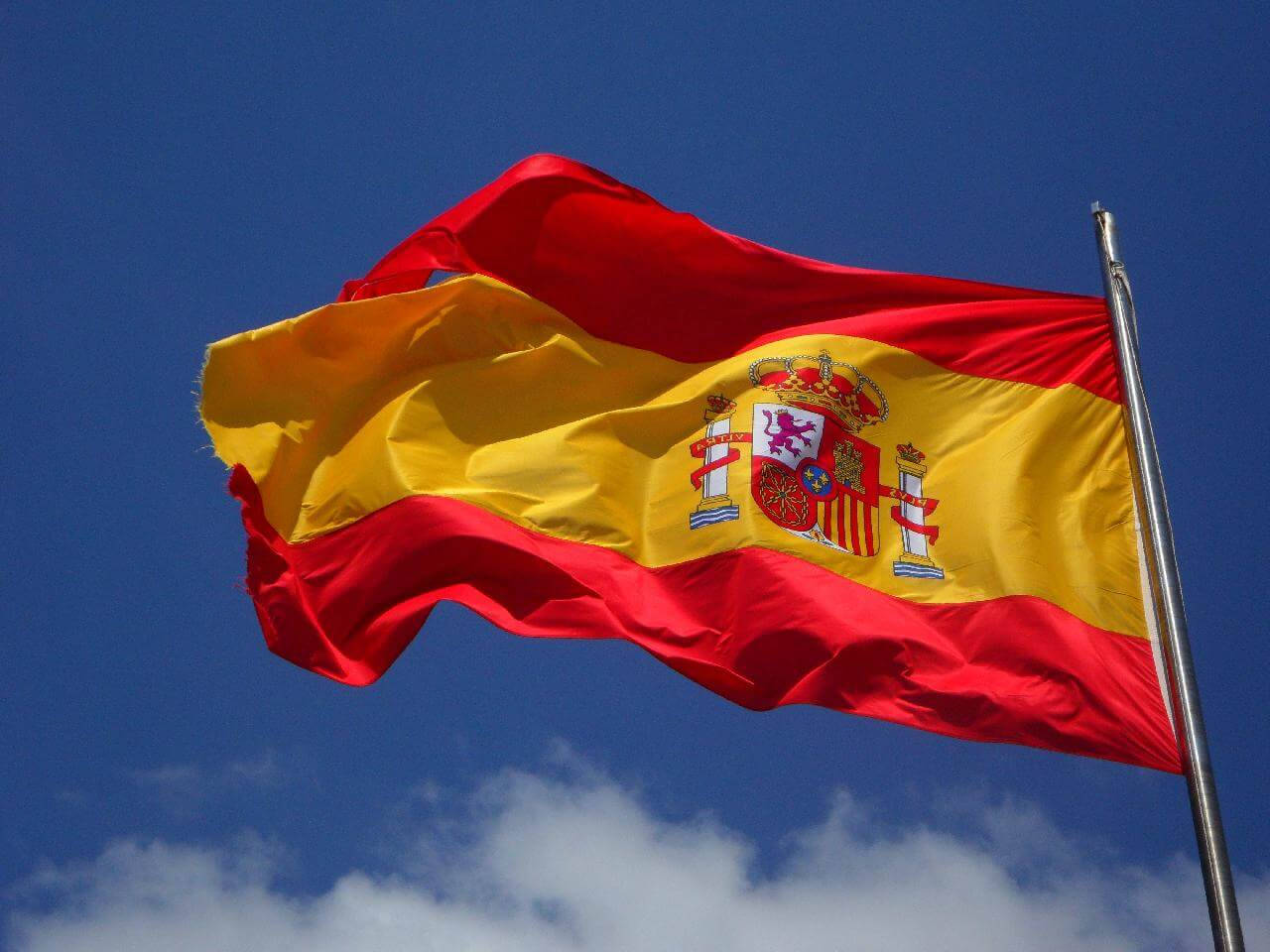 Caption: Spain's National Pride - Magnificent Spain Flag Soaring High Against The Clear Blue Sky Background